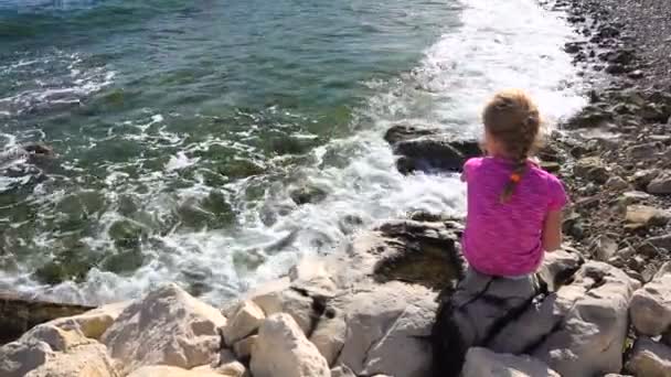 Ragazzina sulla spiaggia, seduta sulle rocce a giocare — Video Stock