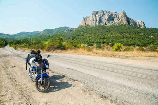 Dağ yolunda kamp malzemeleriyle motosiklet.