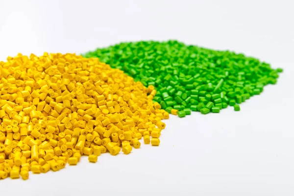 白い背景の上の緑と黄色のプラスチック製のペレット。重合化 — ストック写真