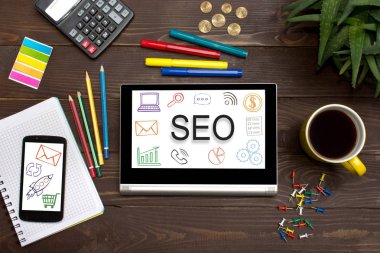 Office araçları ile ahşap bir masa üzerindeki web simgesiyle Seo tablet. 