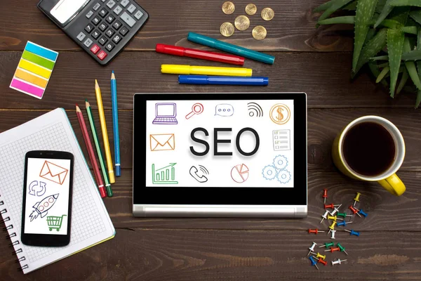 Office araçları ile ahşap bir masa üzerindeki web simgesiyle Seo tablet. 
