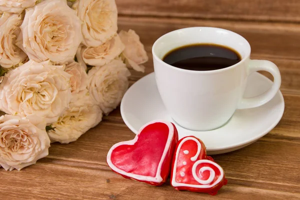 Ημέρα του Αγίου Βαλεντίνου. Φλιτζάνι καφέ και ένα μελόψωμο καρδιά με το υπόβαθρο της ένα μπουκέτο από λουλούδια — Φωτογραφία Αρχείου