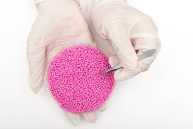 Plastik granül. Renklendirici granül işçi giyen eldiven polimerler için plastik granül cımbızla alır..