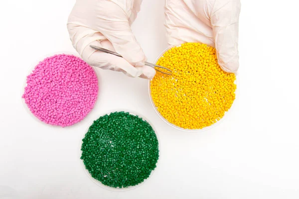 Plastic pellets . Colorant for polymers in granules. Plastic pellets in the hands with gloves and tweezers — Stock Photo, Image