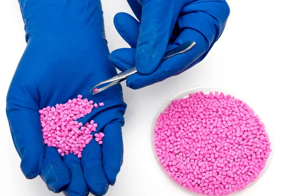 Plastic pellets . Colorant for polymers in granules. Plastic pellets in the hands with gloves — Stock Photo, Image