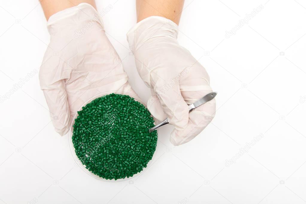 Plastic pellets . Colorant for polymers in granules. Worker wearing gloves takes plastic pellets with tweezers.