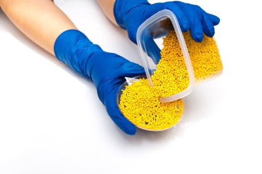 Plastic pellets . Colorant for polymers in granules.Hands in gloves takes plastic pellets clipart