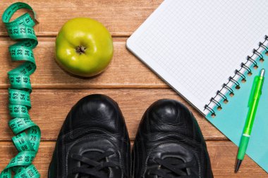 Fitness kavramlar - Spor kıyafetleri ile meyve ve defter, ahşap arka plan