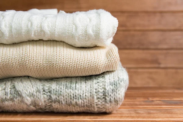 Montón de suéter cálido de punto acogedor, fondo de madera. Suéteres blancos en estilo retro . —  Fotos de Stock