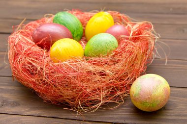 Yuvaya ahşap arka plan üzerinde renkli Paskalya yumurtaları. Yumurta handmad