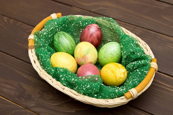 Colorful easter eggs in basket on wooden background. Eggs handma