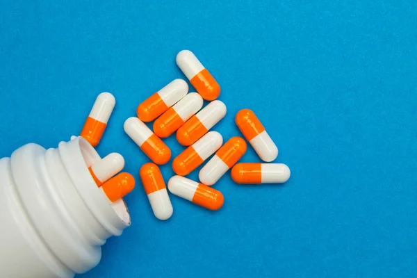 Cápsulas de color blanco anaranjado (pastillas) fueron vertidas de un frasco blanco sobre — Foto de Stock