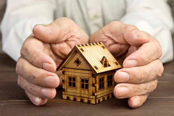 Anciano protegiendo modelo de casa con hands.Risk insurance.The con — Foto de Stock