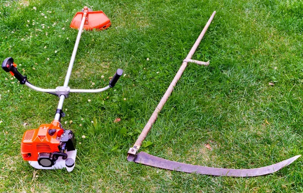 Spit en benzine trimmer voor het maaien van gras, op een groene achtergrond. — Stockfoto