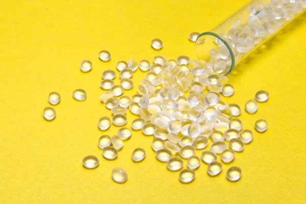 Transparentes Polyethylen-Granulat auf gelbem Hintergrund. — Stockfoto