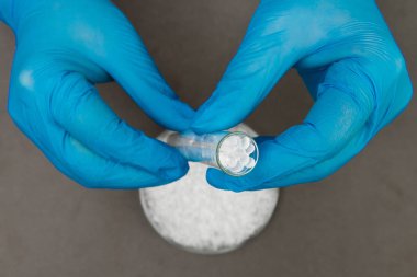Plastik granüller. Polietilen topaklar ve eldivenli eller. Q
