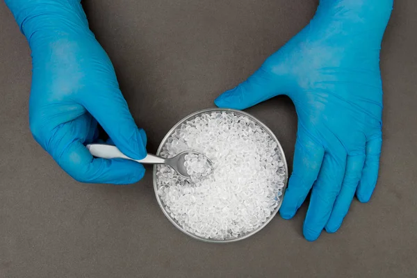 Gránulos de plástico. Pellets de polietileno y manos con guantes. Q — Foto de Stock