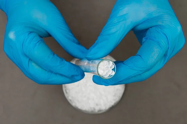 Plastik granüller. Polietilen topaklar ve eldivenli eller. Q