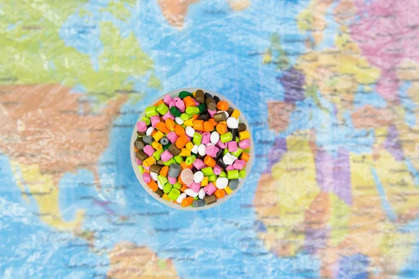 Plastic pellets on the background of the world map in a plastic