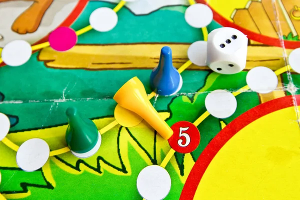 旧棋盘游戏中的蓝色、绿色和黄色塑料筹码和骰子 免版税图库图片