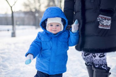 Kış giyinmiş çocuk karlı bir sokakta yürüme