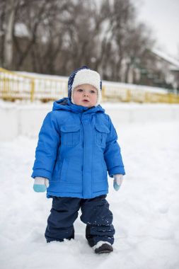 Kış sıcak giyinmiş çocuk karlı bir sokakta yürüme