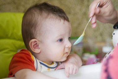 küçük çocuk çocuk sandalyede oturan yiyor