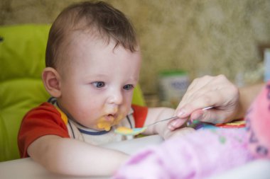 küçük çocuk çocuk sandalyede oturan yiyor