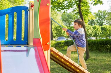 Küçük bir çocuk ipi tutan çocuk tepe tırmanıyor. Bir çocuk Çocuk Bahçesi üzerinde çalış