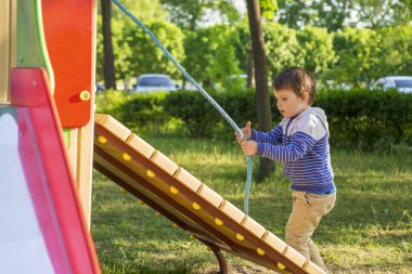 Küçük bir çocuk ipi tutan çocuk tepe tırmanıyor. Bir çocuk Çocuk Bahçesi üzerinde çalış