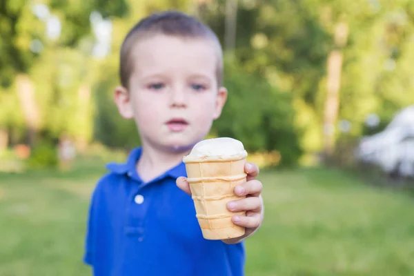 Милый малыш, ешь мороженое. Ребенок держит мороженое в протянутой руке — стоковое фото