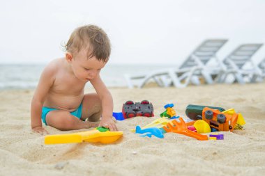 Bebek sahile yakın kumsalda oynuyor.