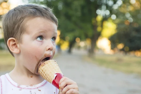 Милый мальчик Тоддлер ест мороженое. ребенок с грязным лицом ест мороженое — стоковое фото
