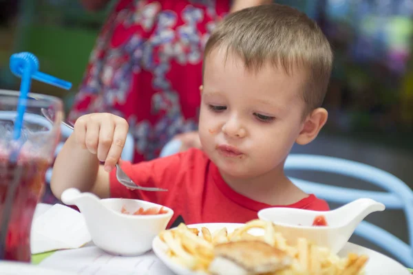 Милый здоровый дошкольный мальчик ест сидя в школе или детском кафе. Счастливый ребенок ест здоровую органическую и веганскую пищу в ресторане. Детство, концепция здоровья — стоковое фото