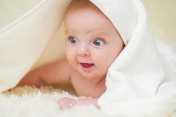 Niño recién nacido relajándose en la cama. Bebé de seis meses con una toalla después de bañarse, en la cama en casa — Foto de Stock