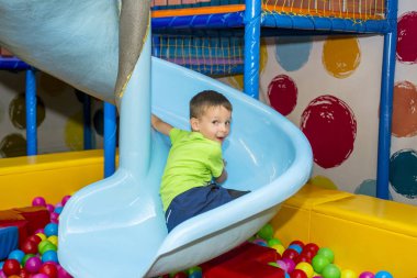 Çocuk parkındaki bir çocuk tepenin üstünde eğleniyor. Çocuk kreşte oynuyor.