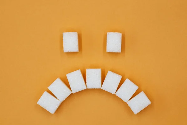 Simbol wajah sedih, terdiri dari batu gula. Konsep gula yang mengarah ke karies. Kerusakan kesehatan karena gula — Stok Foto