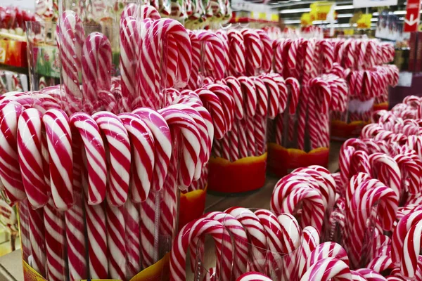 Christmas candy canes in store. Festive red and white peppermint candy canes background. Candy canes with red and white stripes