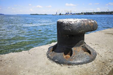 Denizci gemisi su kenarındaki rıhtımda demirliyor.