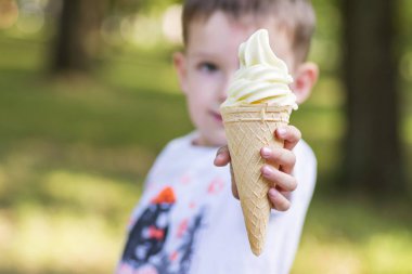 Güzel bebek, elinde dondurmayla waffle konservesi tutuyor. Güzel küçük çocuk dışarıda dondurma tutuyor.