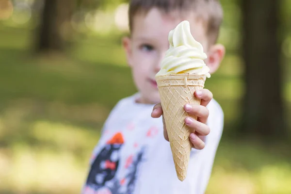Симпатичный малыш держит мороженое в руках в вафельном соусе. Красавчик держит мороженое на улице. — стоковое фото