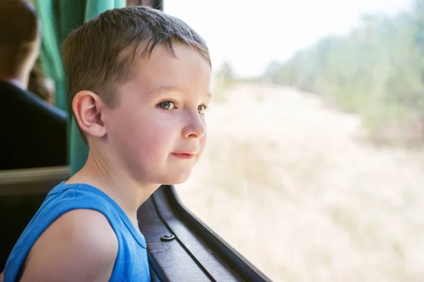 Anak itu bepergian dengan kereta api dan melihat melalui jendela, menonton benda bergerak di luar jendela. Anak laki-laki di kereta oleh jendela — Stok Foto