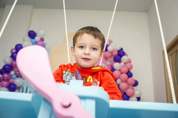 Chlapec si představuje sám sebe jako pilota letadla v dětském pokoji. Šťastné dítě na koni na hračce letadlo — Stock fotografie