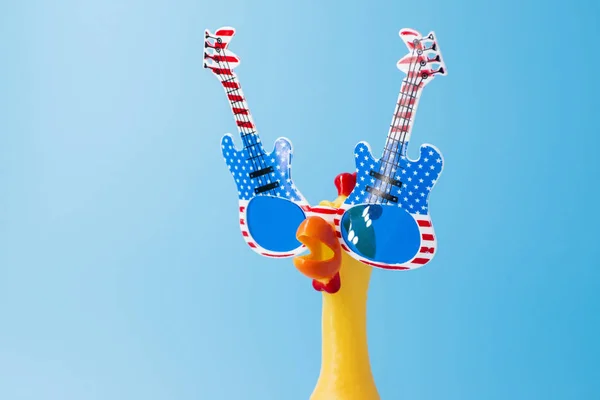 Screaming toy chicken in glasses on a blue background. Toy yellow shrilling chicken on blue background. Copyspace — Stock Photo, Image