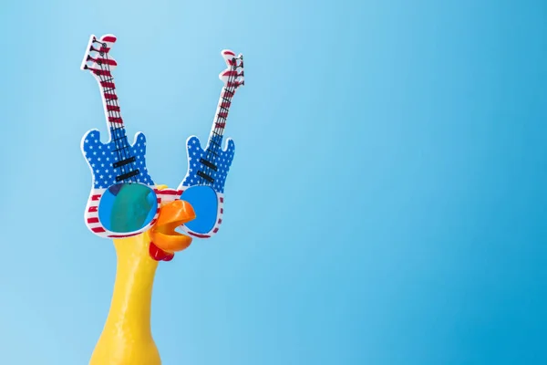 Gritando pollo de juguete en vasos sobre un fondo azul. Juguete amarillo chillón pollo sobre fondo azul. Espacio de copia — Foto de Stock