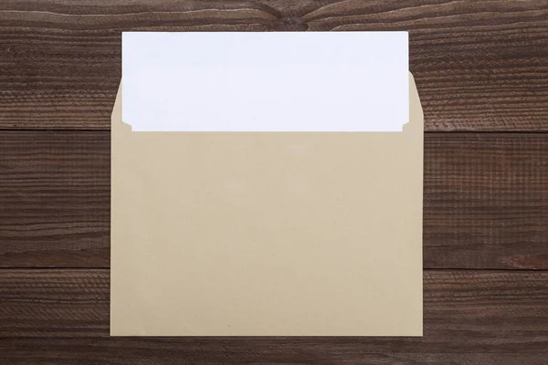 Leere weiße Karte und Umschlag auf dem Holztisch. ein offener leerer lebhafter gelber Umschlag mit weißem Papier auf hölzernem Hintergrund — Stockfoto