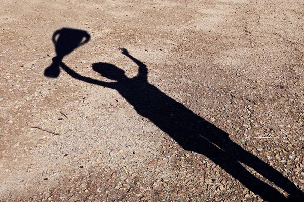 Silhouette of man. Shadow of a man with a cup in his hand. Triumph concept. Successful person raise hand. Triumph and victory