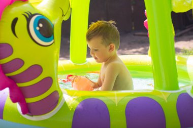 Çocuklar oyun oynuyor ve boş zamanlarında yüzme havuzu konsepti. Yazın eğlenen bir çocuk. Küçük çocuk havuzda eğleniyor.