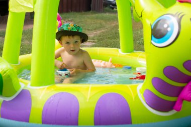 Çocuklar oyun oynuyor ve boş zamanlarında yüzme havuzu konsepti. Yazın eğlenen bir çocuk. Küçük çocuk havuzda eğleniyor.