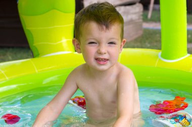 Çocuklar oyun oynuyor ve boş zamanlarında yüzme havuzu konsepti. Yazın eğlenen bir çocuk. Küçük çocuk havuzda eğleniyor.